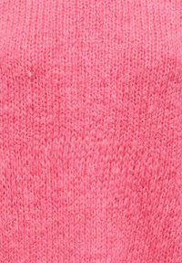 Gros plan sur un tissu rose doux et texturé en tricot avec un motif de torsades visible et des fibres de fil moelleuses.