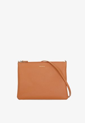 Sac bandoulière en cuir fauve à texture granuleuse, fermeture éclair dorée, sangle fine et petit logo doré « Coccinelle » centré près du haut.