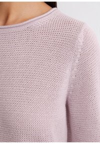 Jasnoróżowy sweter dzianinowy, z oddychającym, otwartym splotem, okrągłym dekoltem i ściągaczami wzdłuż brzegów.