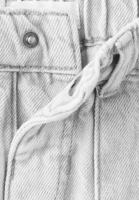 Vaaleanharmaa farkkukangas, jossa on lähikuva nappikiinnityksestä ja vyötärönauhasta. Kankaan pinta on pehmeä ja siinä näkyy ompelusaumat selvästi.