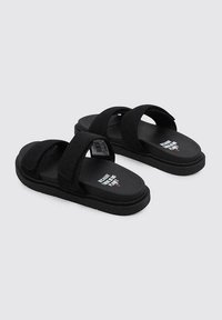 Chanclas negras con dos anchas correas de tela, suela de goma y texto impreso en la plantilla. Diseño minimalista sin acentos adicionales.