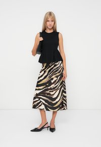 Black peplum top with a round neckline and a patterned, floor-length skirt featuring beige and brown tiger stripes. Black slingback heels.