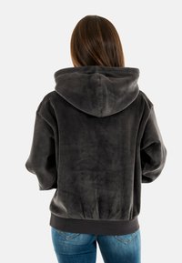 Fluffy zwarte hoodie met een zachte textuur, oversized pasvorm en een capuchon. Heeft een geribbelde zoom, met een eenvoudige achterkant zonder zichtbare hardware.