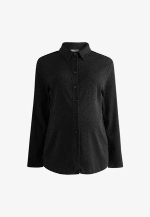 Schwarzes Hemd mit langen Ärmeln, strukturierter Stoff, klassischer Kragen und vorderer Knopfverschluss. Verfügt über einen leicht abgerundeten Saum.