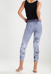 Leggings in lichtblauw met een textuurpatroon en donkerblauwe abstracte accenten. Hoge tailleband en slimfit ontwerp, geschikt voor actieve kleding.