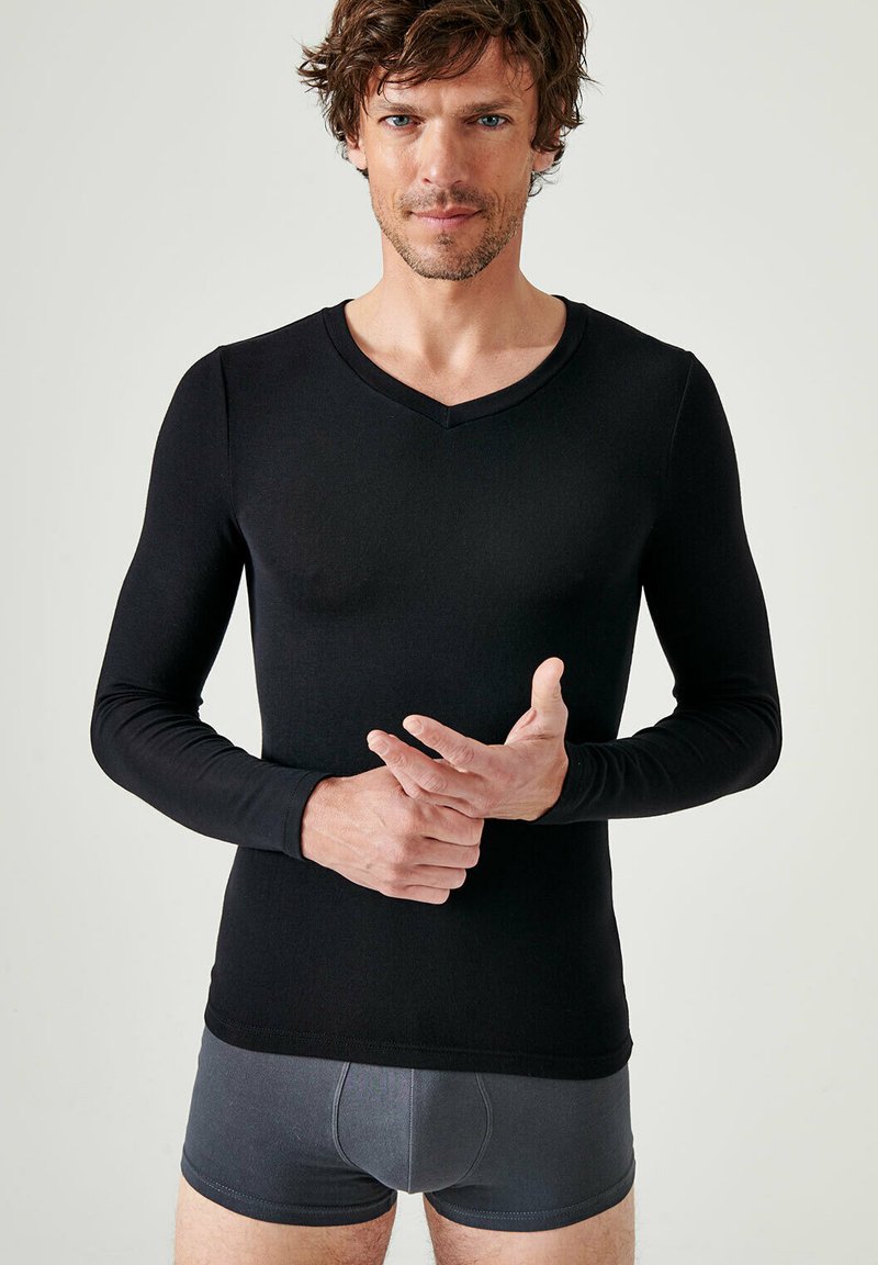 Black long-sleeve V-neck shirt made of a smooth fabric, fitted design, worn over gray fitted underwear. Minimal seams, clean silhouette.