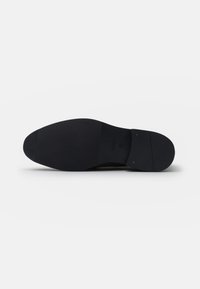 Suela de zapato de cuero negro con una superficie lisa y texturizada. Presenta puntera redondeada y el nombre de la marca "JOOP!" en relieve, junto con la talla "41".