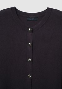 Cardigan en tricot violet foncé avec un col rond et cinq boutons métalliques à l'avant, étiquette de marque visible.