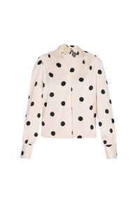 Blusa crema con ampie pois neri, colletto alto, maniche lunghe con polsini arricciati e un accento floreale decorativo.
