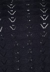 Tissu en tricot noir avec un motif texturé présentant des formes en zigzag et des sections en maille ouverte, mettant en avant un design géométrique.