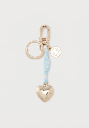 Auksuoto metalo raktų pakabukas su užsegimu, apvalus žavesys su raide „G“, šviesiai mėlynos spalvos audinio mazgas ir širdies formos žavesys su įrašu „GUESS“.