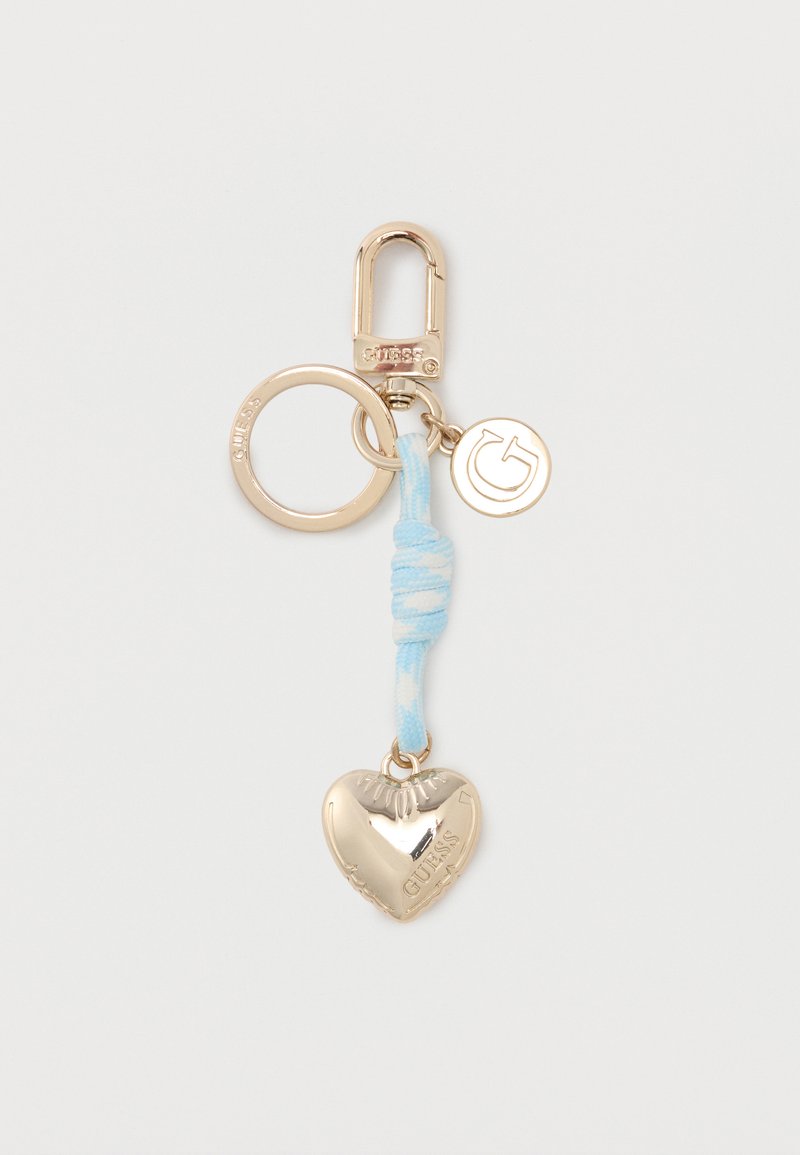 Μπρελόκ από μέταλλο σε χρυσό τόνο με κλιπ, στρογγυλό φυλαχτό με το γράμμα "G", φωτεινό γαλάζιο υφασμάτινο κόμπο και φυλαχτό σε σχήμα καρδιάς με χαραγμένο το "GUESS".