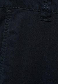 Donkerblauwe denimstof met een gladde textuur, voorzien van zichtbare stiksels, een riemlus en een subtiel diagonaal patroon.