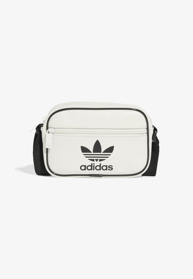 Balta sintetinio audinio krepšys su juodomis detalėmis, turintis priekinį užtrauktuką, iškilų Adidas logotipą ir reguliuojamą diržą. Stačiakampio formos.