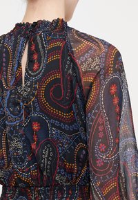 Εκτυπωμένο μπλουζάκι από chiffon με σχέδιο paisley σε κόκκινο, μπλε και πορτοκαλί, με gathered λαιμόκοψη και διαφανή μακριά μανίκια.