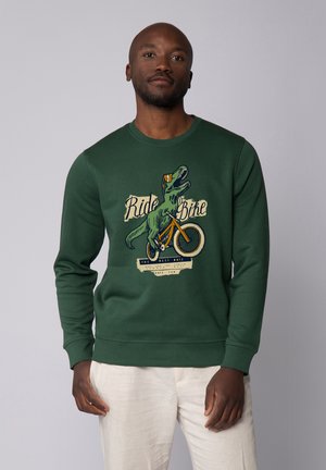 Sweatshirt vert avec un graphisme d'un dinosaure sur un vélo portant le texte "Fais du vélo". Tissu doux, col ras du cou et poignets côtelés.