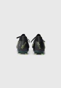 Black soccer cleats with a textured surface, green accents, and a low-cut design. Features a snug fit and a lightweight construction.