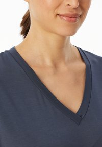 Navy V-Neck T-Shirt mit einer glatten, weichen Textur. Der Ausschnitt hat einen sauberen, gestickten Rand, und der Stoff wirkt leicht und atmungsaktiv.