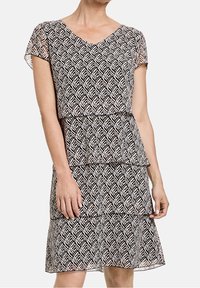 Vestido de patrón blanco y negro con escote en V, mangas cortas, diseño en capas y texturas geométricas.