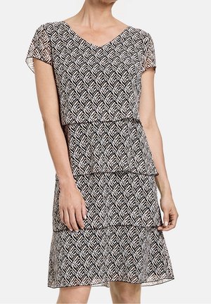 Robe à motifs noir et blanc avec décolleté en V, manches courtes, design empilé et textures géométriques.