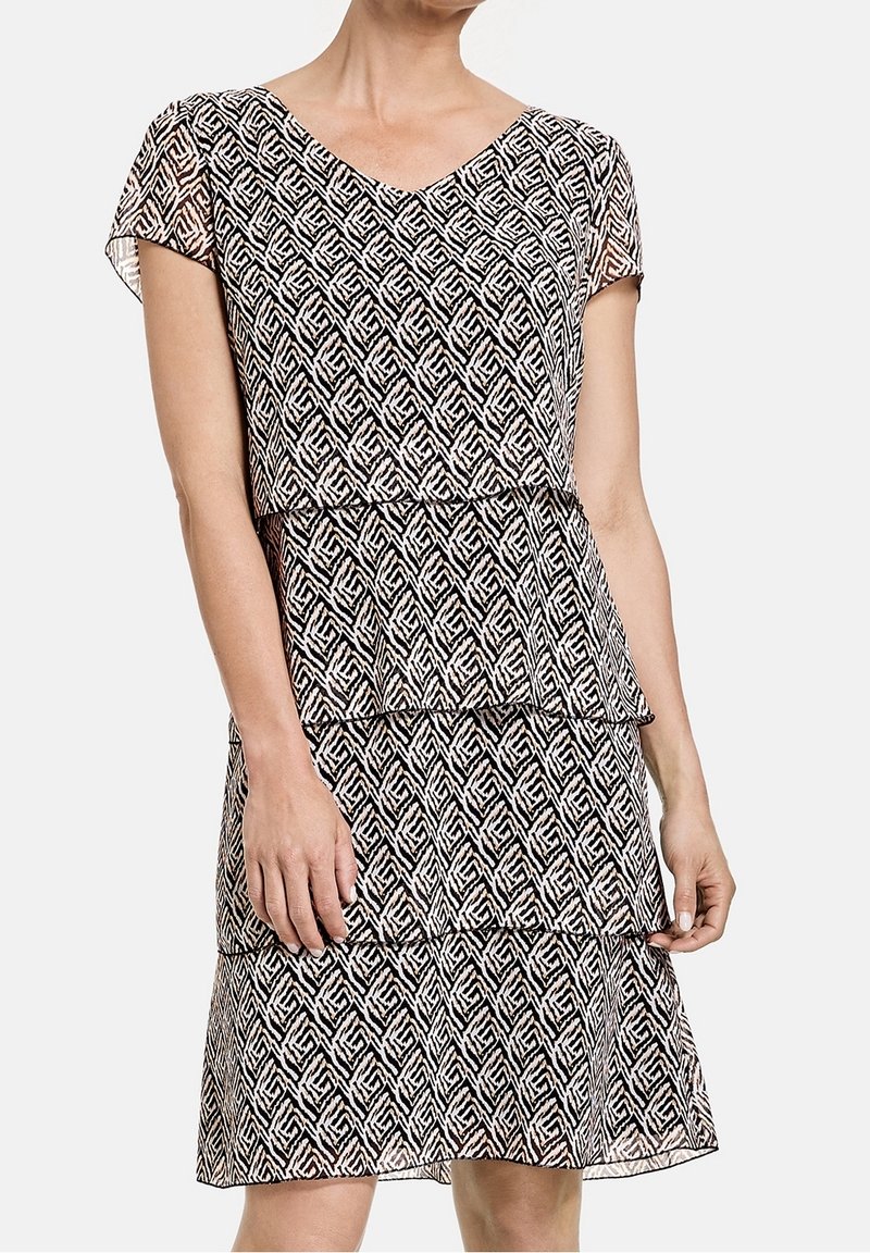 Vestido de patrón blanco y negro con escote en V, mangas cortas, diseño en capas y texturas geométricas.