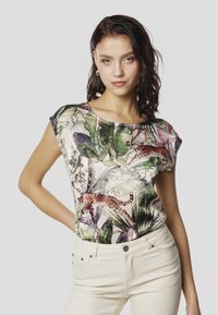 Īsroku tops ar košu ziedu un dzīvnieku rakstu zaļā, rozā un brūnā krāsā. Gluda auduma, apaļa kakla izgriezums, brīvs piegriezums.