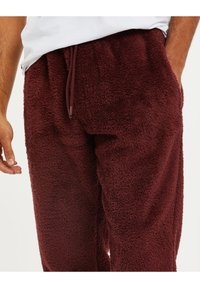Bordeaux fleece joggingbroeken met een zachte, gestructureerde oppervlakte en een verstelbare trekkoordtaille. Beschikt over een ontspannen pasvorm en elastische boorden bij de enkels.