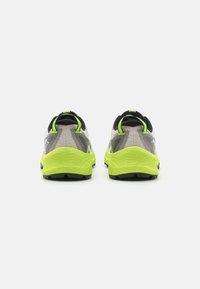 Zapatillas de correr con una parte superior de malla gris, detalles en negro y una suela amarilla brillante. Presentan un diseño texturizado con un patrón de banda circular.