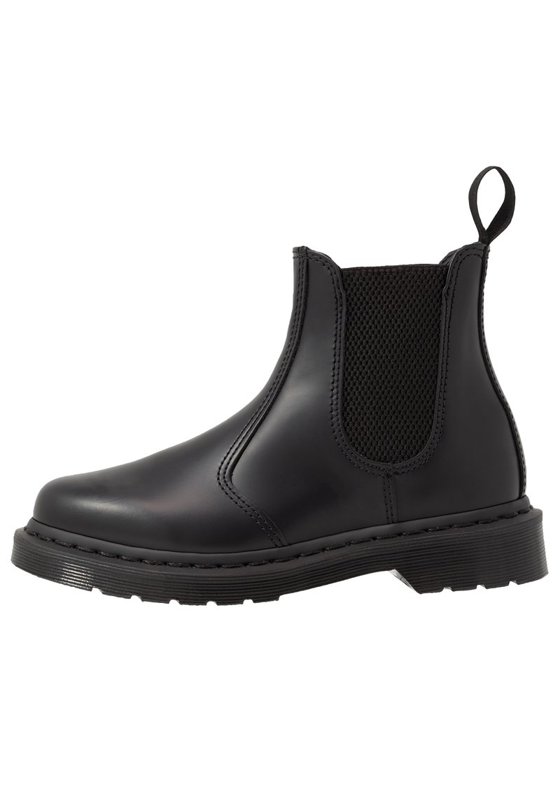 Bottine en cuir noir avec panneau latéral élastique, languette de tirage à l'arrière, semelle épaisse et détails cousus sur fond blanc.