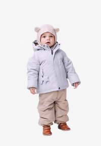 Svetlo siva izolirana jakna z zvezdnim zakrpom, bež hlače in rjavi škornji; vključuje klobuk z ušesi medvedka in zadrgo.