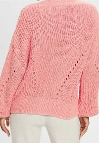 Pull en tricot rose à coupe décontractée, avec un motif texturé et des détails de mailles ouvertes sur les manches et le dos.