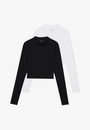 Kaksike losanga varrukatega soojad, mustad ja valged crop tops. Valmistatud pehmest kangast, ümarate kaelustega ja täpselt istuvast siluetist.