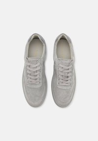 Sneaker grigie in suede con punta rotonda, lacci piatti e una morbida accentuazione in pelle grigia sul tallone. Design minimalista e texture superficiale liscia.