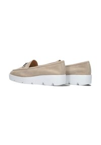 Beige suède instappers met een gladde textuur, een dikke witte rubberen zool en een subtiel decoratief element op het bovenste gedeelte.