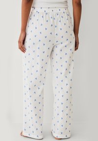 Witte pyjamabroek met blauwe hartpatronen, gemaakt van textuurstof. Voorzien van een elastische tailleband en een wijde pijpdesign.