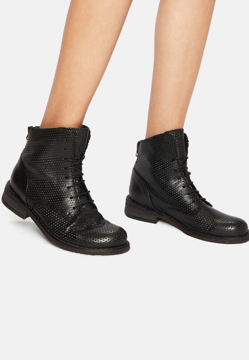 Botas de tobillo de cuero negro con un diseño perforado, cordones y un panel lateral texturizado; terminadas con un tacón de madera bajo.