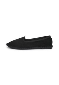 Chaussure slip-on en suede noire avec un orteil arrondi, un bord élastique et une semelle texturée, présentant un détail tressé le long du bord.