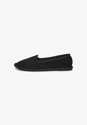 Scarpa nera in suede con punta arrotondata, bordo elastico e suola texturizzata, caratterizzata da un dettaglio intrecciato lungo il bordo.