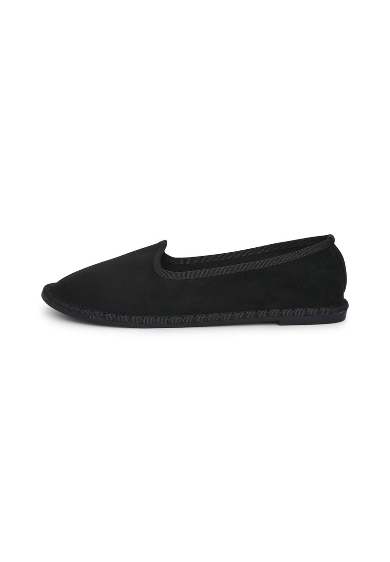 Chaussure slip-on en suede noire avec un orteil arrondi, un bord élastique et une semelle texturée, présentant un détail tressé le long du bord.