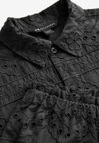 Set di blusa nera ricamata e gonna abbinata. Presenta motivi floreali, tessuto testurizzato e chiusura a bottoni sul colletto della blusa.