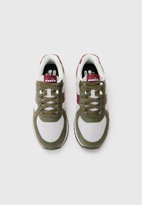 Green and white athletic shoes with a mesh upper, suede accents, round laces, and a contrasting maroon stripe. Logo on the tongue.