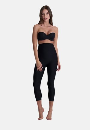 Leggings noires taille haute en tissu extensible, présentant une texture lisse et un design ajusté qui s'étend jusqu'à la mi-mollet.