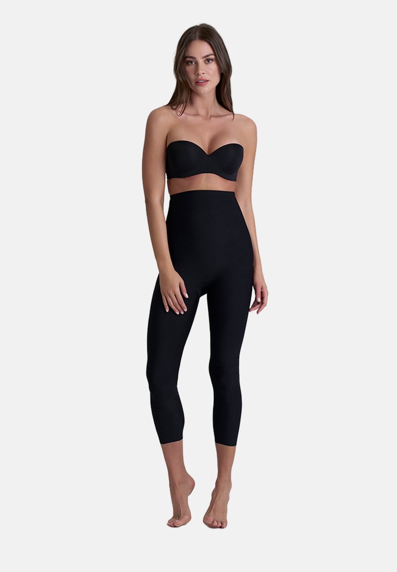 Leggings neri a vita alta in tessuto elastico, con una texture liscia e un design aderente che si estende fino alla metà del polpaccio.