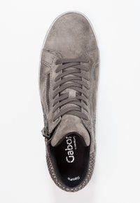 Šedé semišové tenisky s texturovaným bočním akcentem, šněrováním a bočním zipem. Černá stélka s viditelným logem uvnitř.