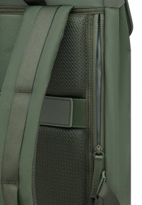 Groene stoffen rugzaksectie met een geperforeerd gaas en gladde accenten. Beschikt over een rits en verstelbare banden. Duurzaam materiaal en een gestructureerd ontwerp.