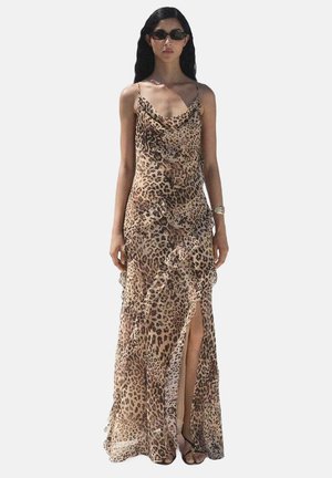 Leopard print maxi dress with ruffled design, sheer fabric, and a thigh-high slit; accessorized with sunglasses and a bracelet.