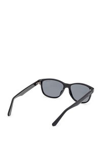 Svarta solglasögon med en elegant, kantig design. Mörka linser, plastbåge, texturerade detaljer vid templet, smala skalmar som smalnar av mot ändarna.