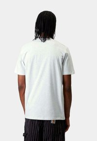 Camiseta de algodón gris claro con mangas cortas, diseño simple y cuello redondo, vista desde la parte posterior. Sin gráficos ni patrones visibles.