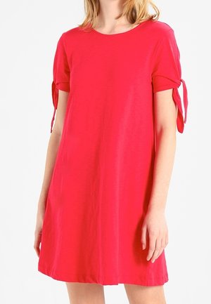 Robe à manches courtes, de forme A, en rose vif, fabriquée en tissu lisse. Présente des liens noués aux manches et un col rond.