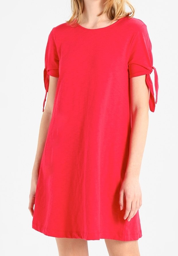 Robe à manches courtes, de forme A, en rose vif, fabriquée en tissu lisse. Présente des liens noués aux manches et un col rond.